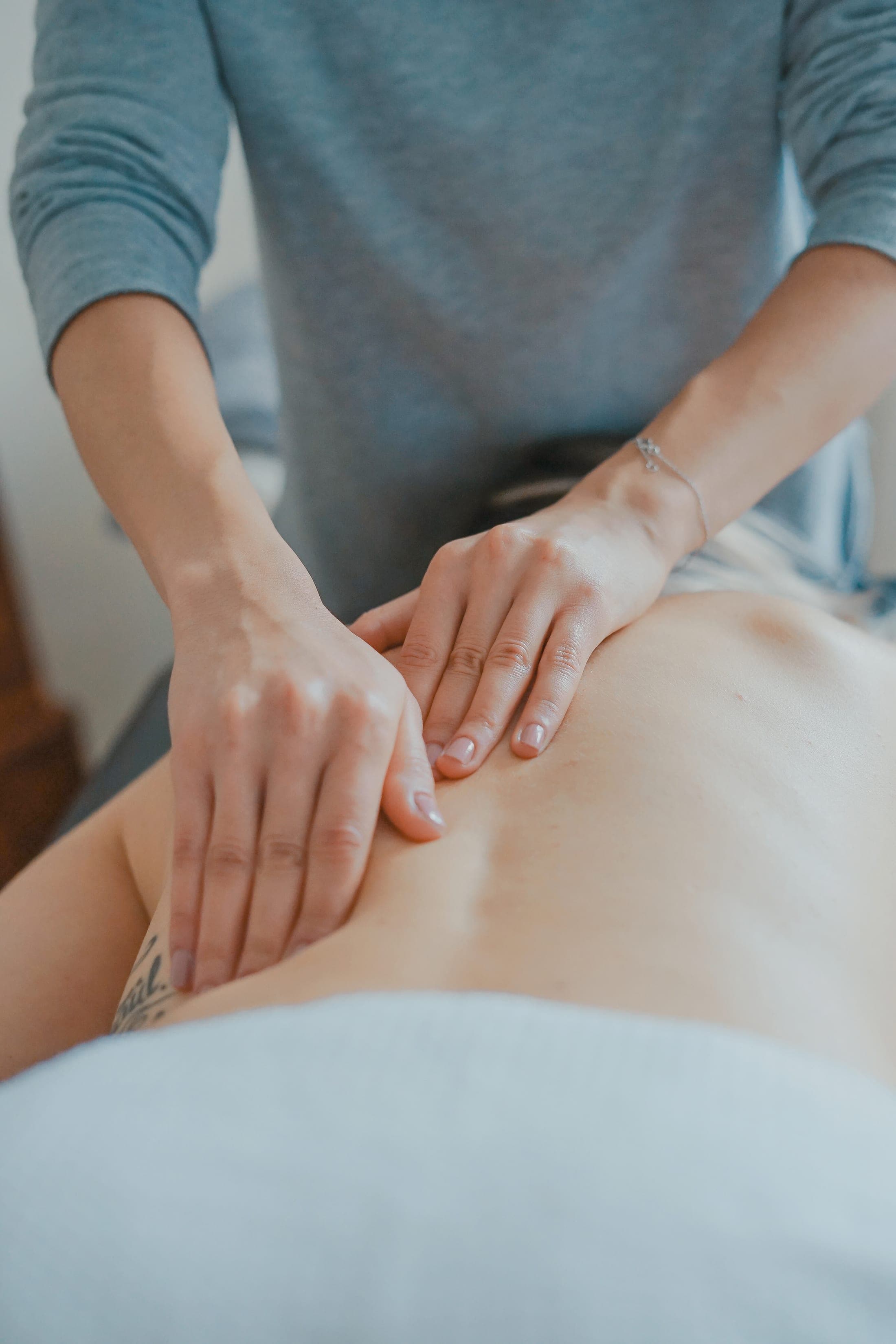 Hands of a registered massage therapist working a client's shoulder