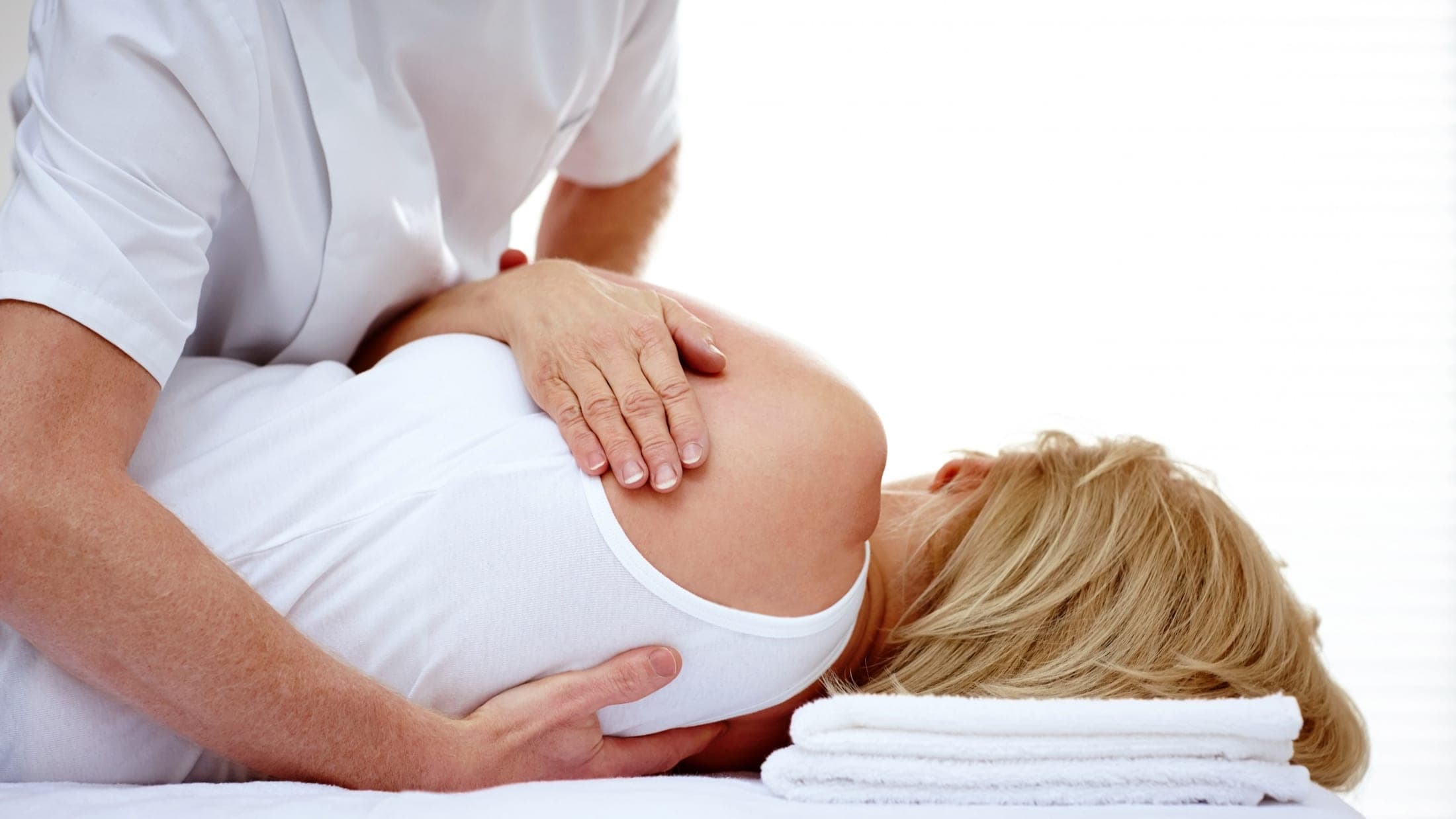 Manual osteopath assessing a client's lower spine